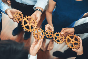Office worker holding cog wheel as unity and teamwork in corporate workplace concept. Diverse colleague business people showing symbol of visionary system and mechanism for business success. Concord
